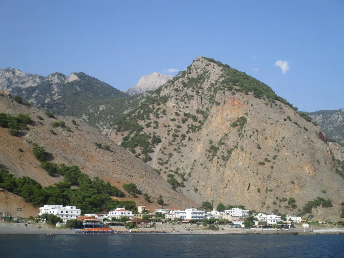 Agia Roumeli vom Meer aus: eine Reihe weißer Gebäude am Fuß steiler, bewaldeter Berge