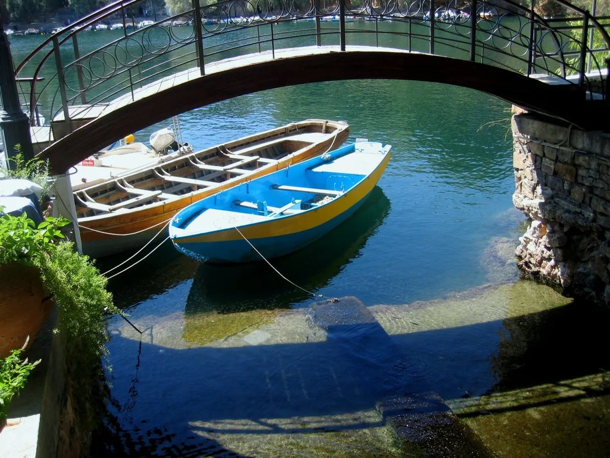 Wooden boats moored under the footbridge on Lake Voulismeni at Agios Nikolaos