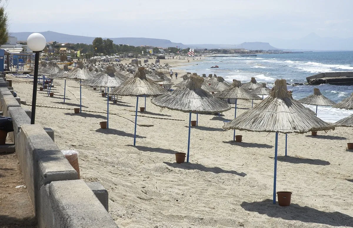 A row of straw umbrellas along the low seafront at Anissaras