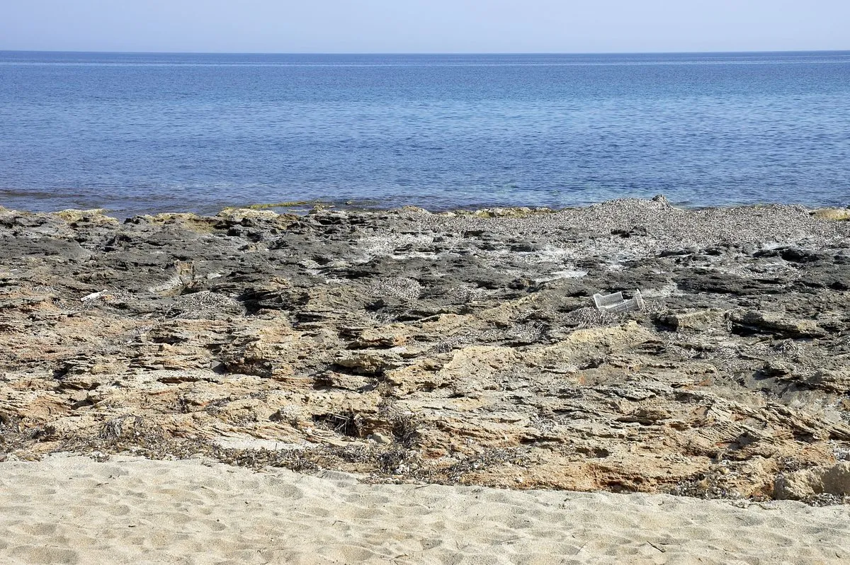 The low limestone shore at Anissaras, flat rock running into clear water