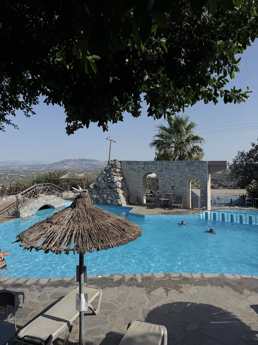 The pool at Arolithos, with a thatched umbrella and the view west over the valley