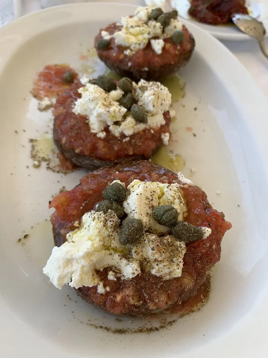 Ein Teller Dakos mit Tomaten, Käse und Kapern