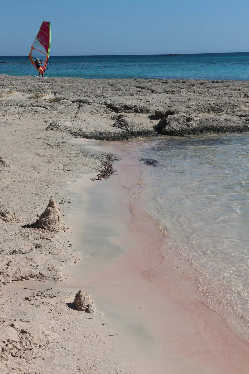 Rosa schimmernder Sand an der Wasserlinie am Strand von Elafonisi