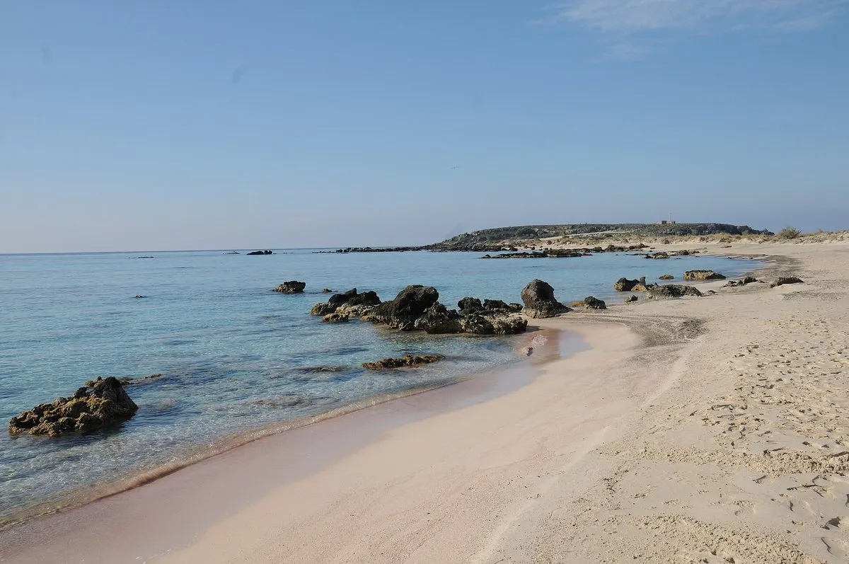 The pink-tinted sand at the water's edge