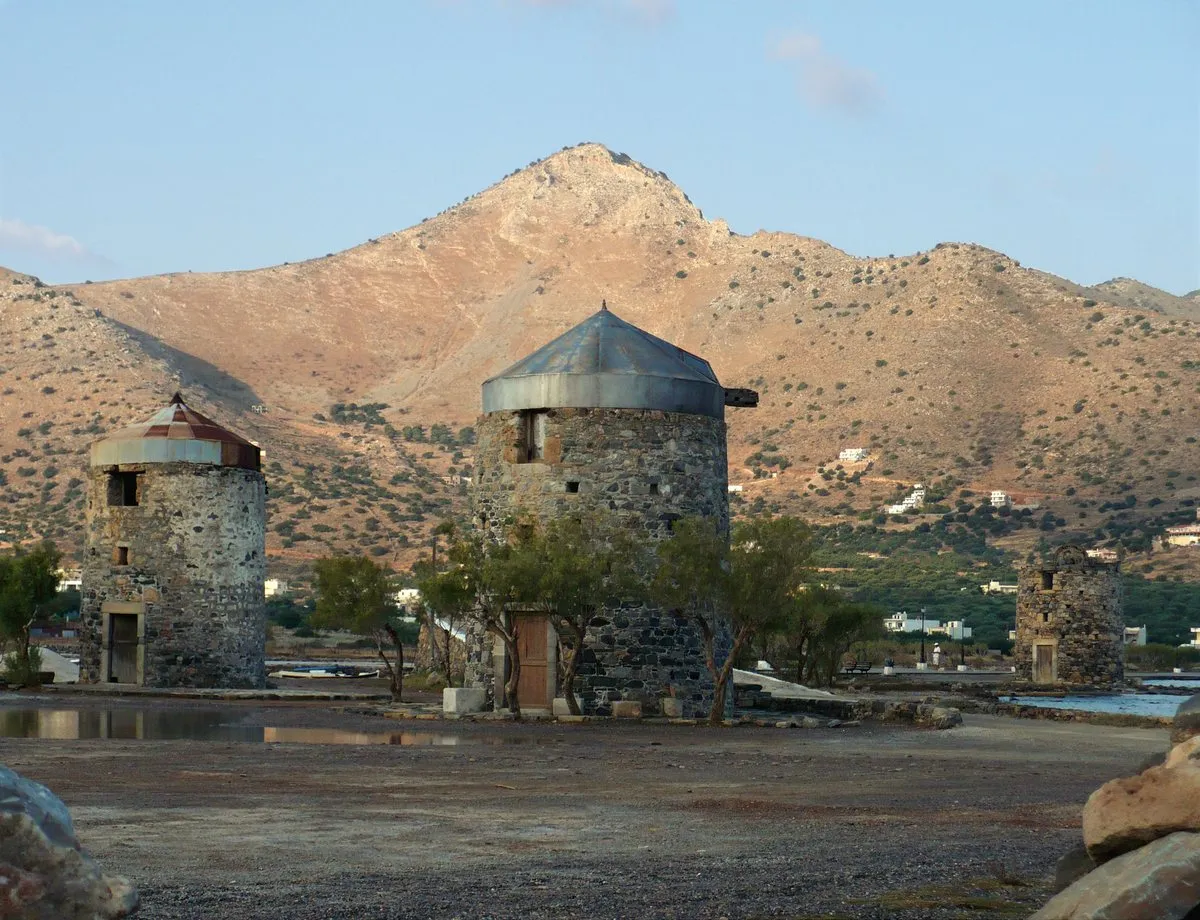 The row of stone windmills beside the Elounda causeway, under the bare mountain
