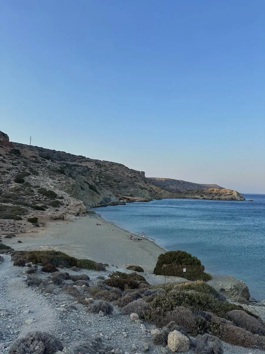 The bay at Erimoupolis in late afternoon light, a gravel track leading down to nearly empty sand