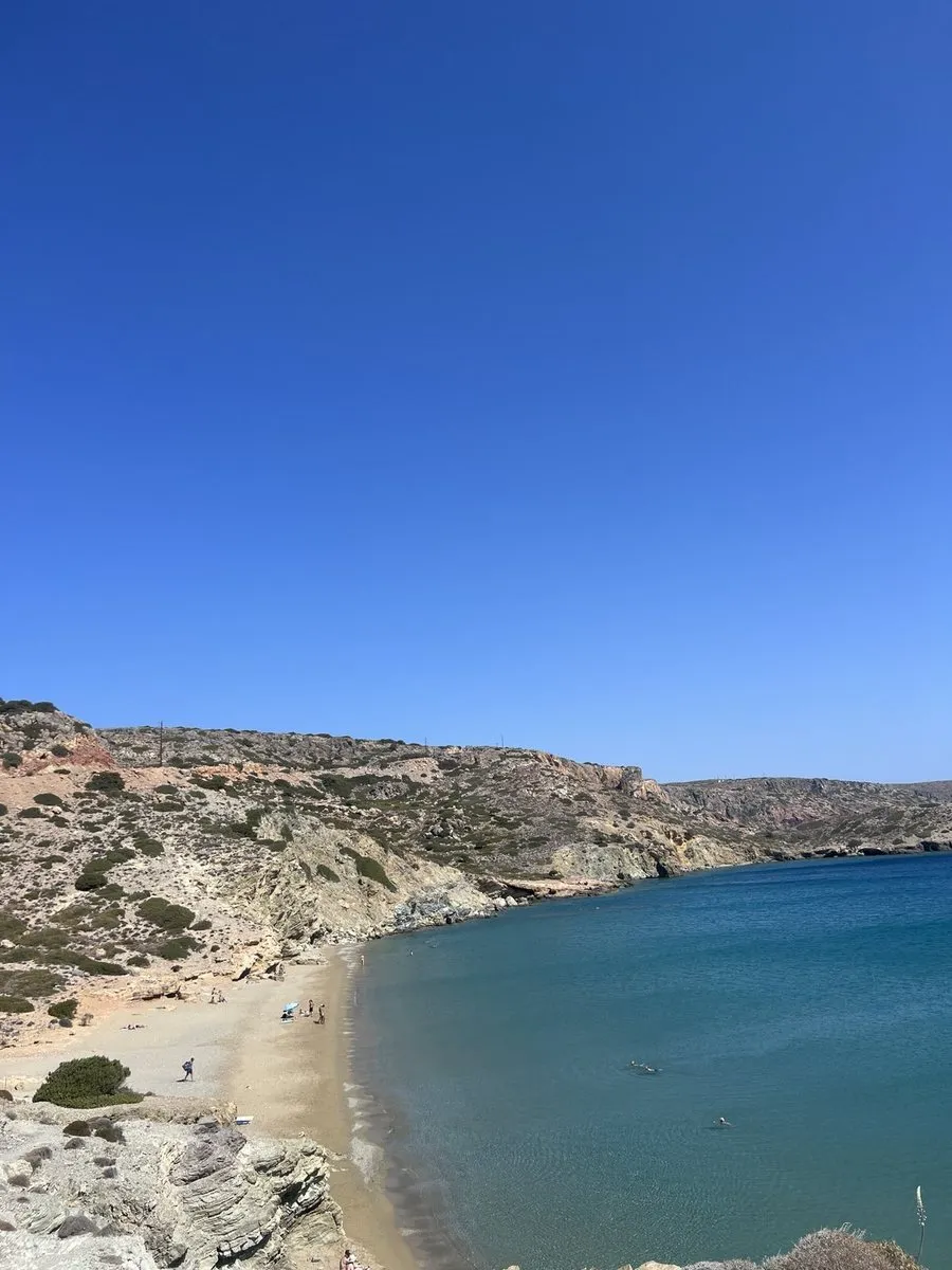 Sandy cove at Erimoupolis seen from the road above, with turquoise water and dry rocky hills around it