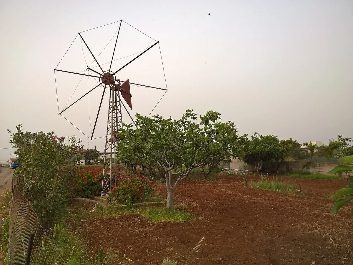 Ein altes Windpumpenrad über einem Gemüsegarten in Kato Gouves