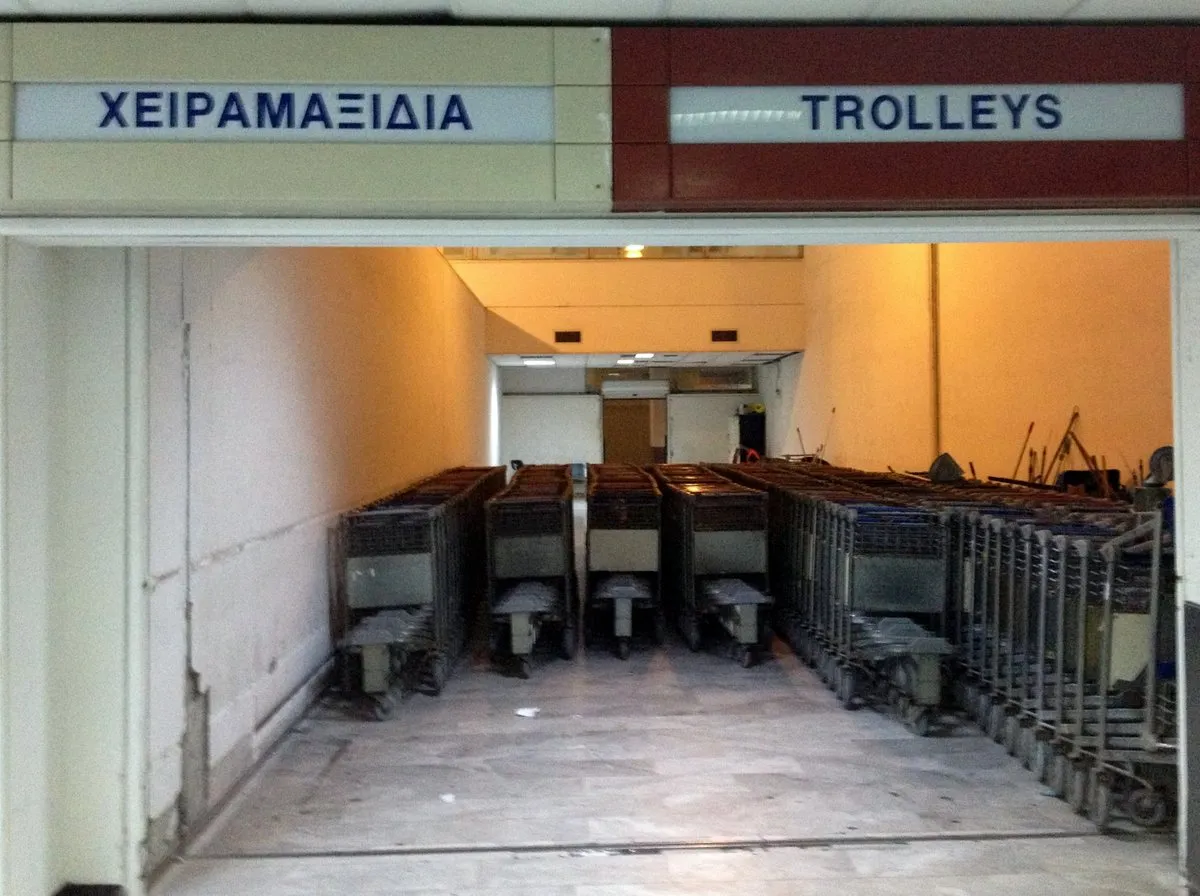 Eine Reihe Gepäckwagen am Flughafen Heraklion unter einem Schild mit der Aufschrift Trolleys auf Griechisch und Englisch