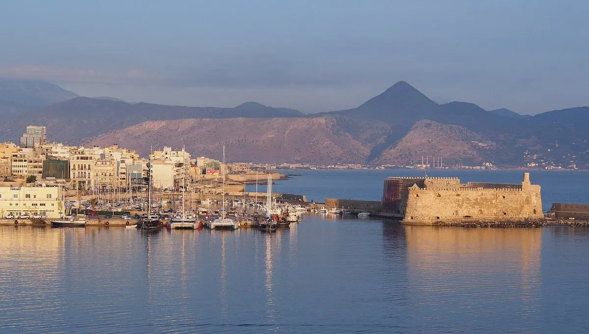 Der alte Hafen von Heraklion mit Fischerbooten, der Festung und den Bergen dahinter