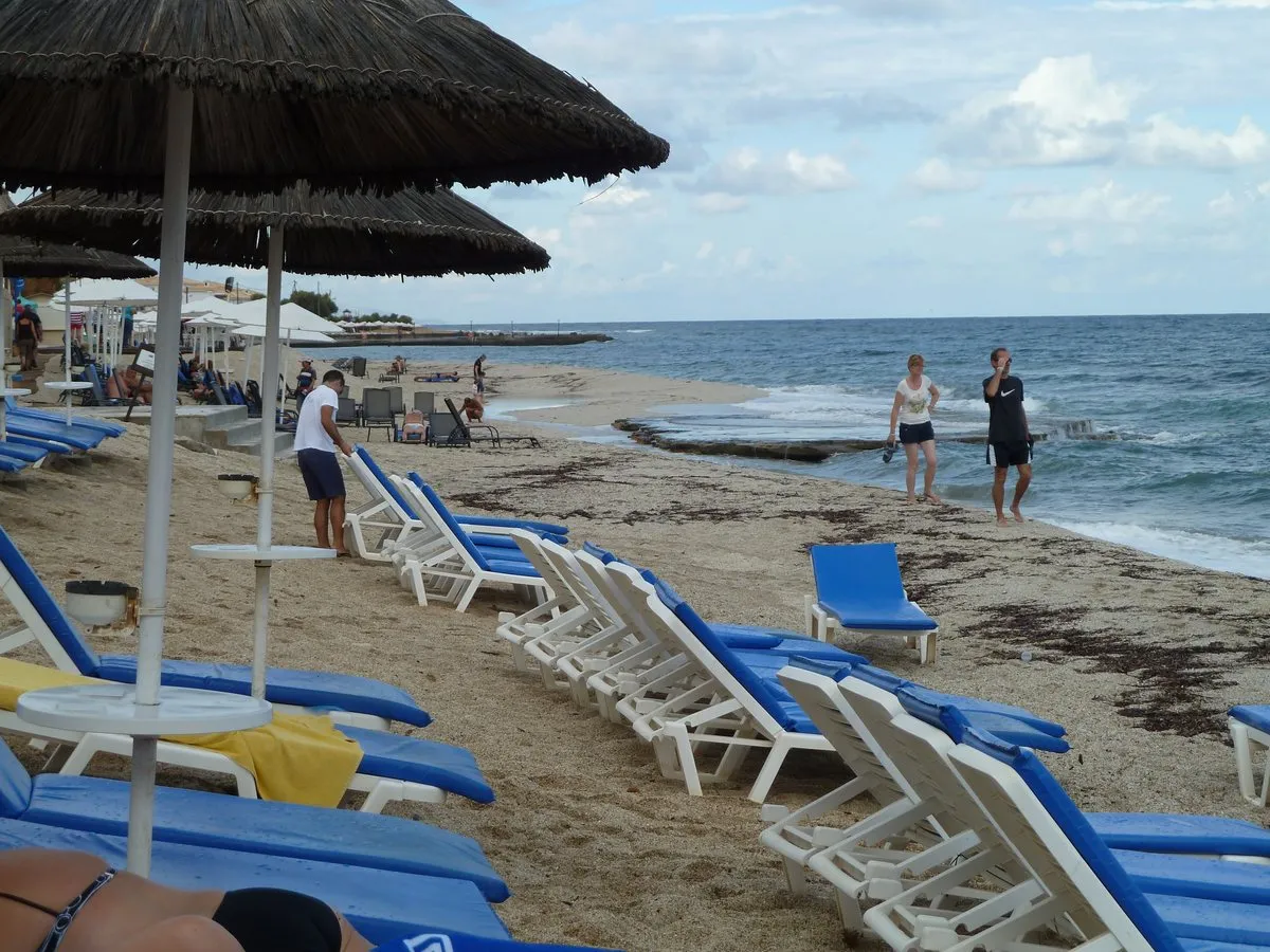 A narrow strip of town-front sand at Hersonissos with rows of sunbeds and umbrellas down to the water