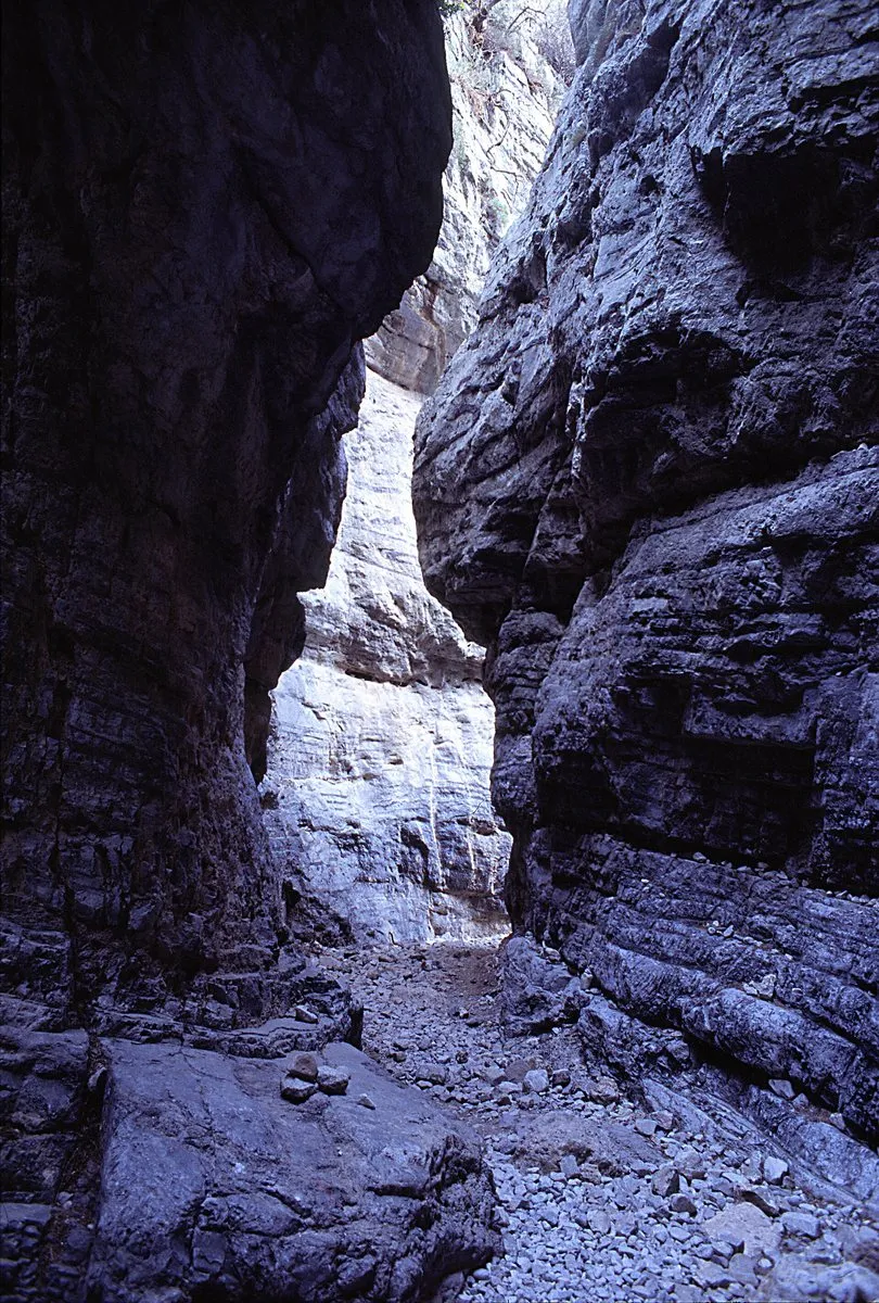 The narrowest point of Imbros Gorge, pale limestone walls closing to a gap barely wide enough for one person
