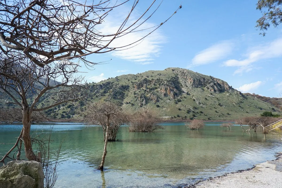 Lake Kournas ringed by hills, a bare tree in the shallows