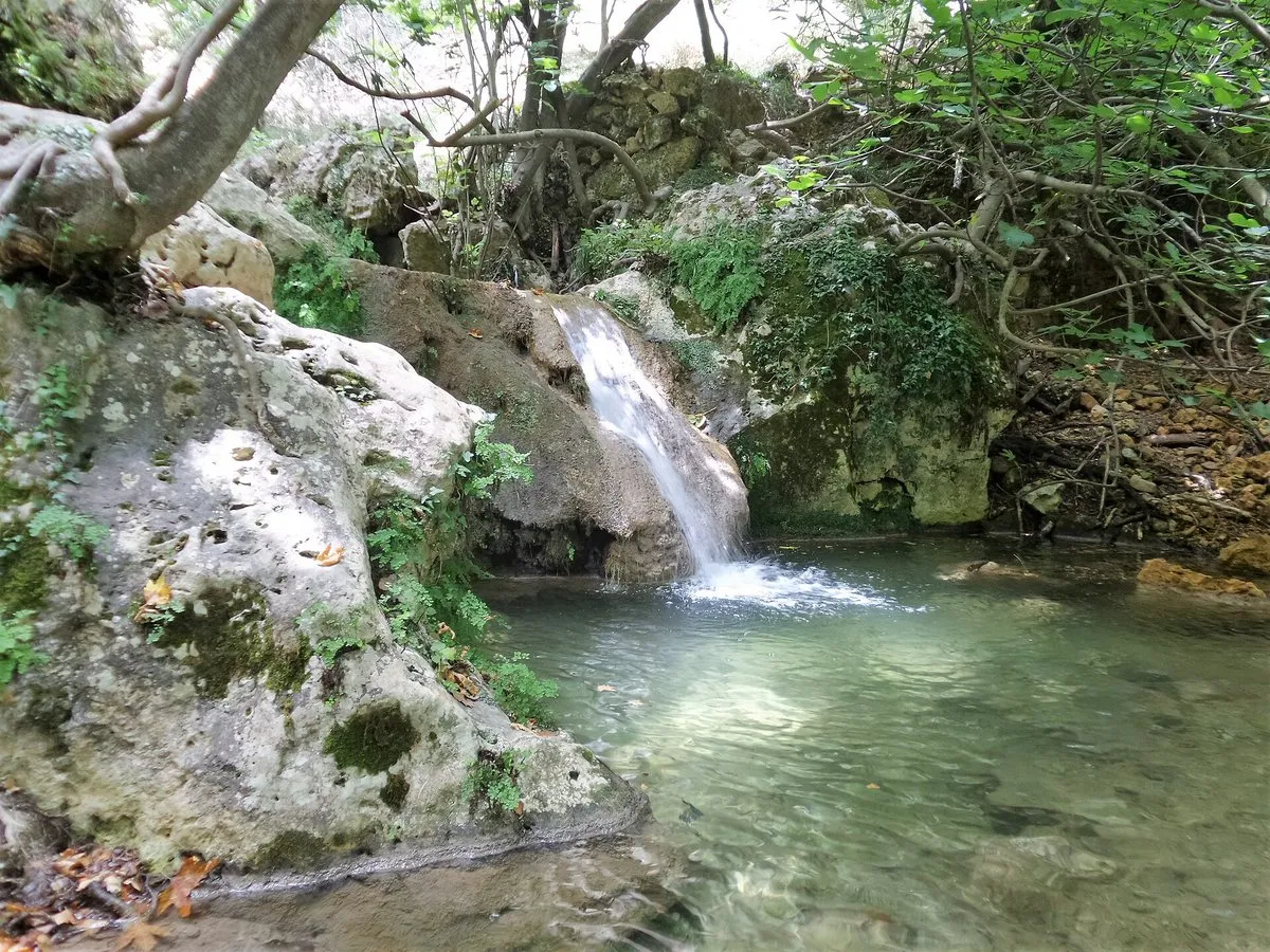 Ein kleiner Wasserfall, der in ein klares grünes Becken in der Myli-Schlucht fällt