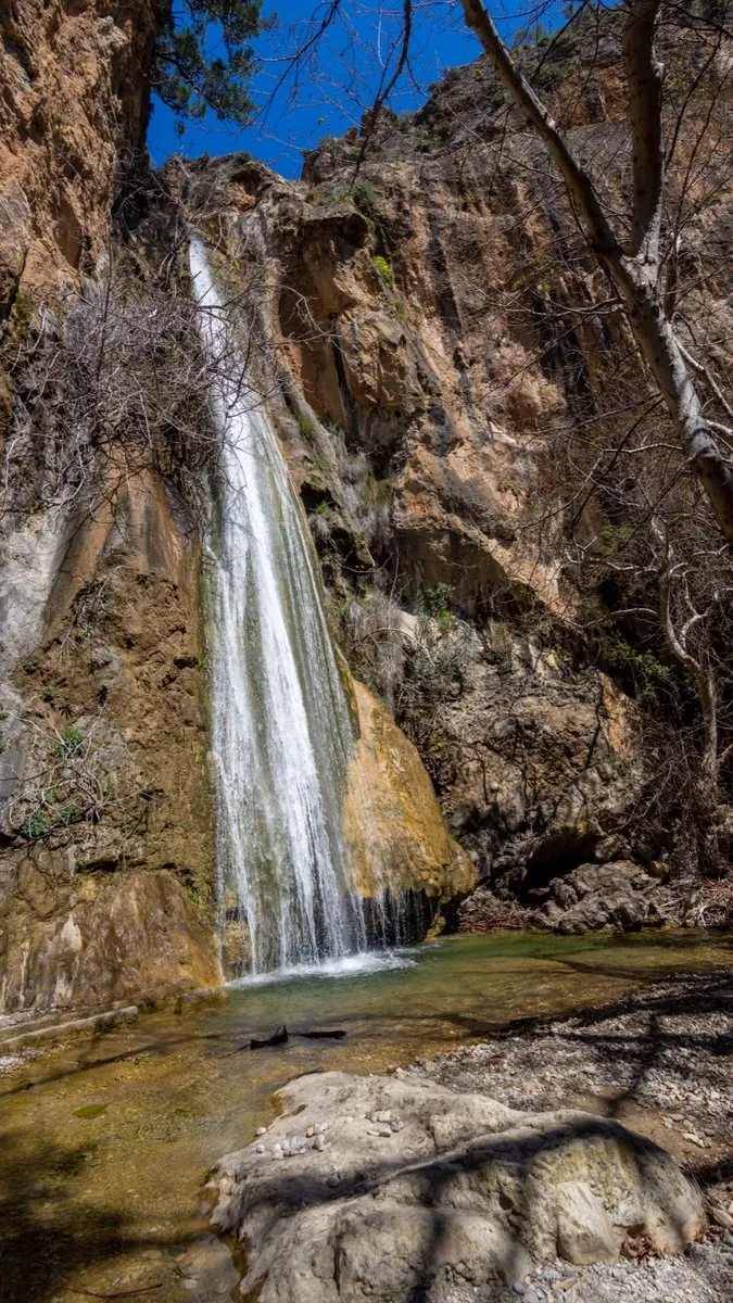 Ein hoher, schmaler Blick auf den Mylonas-Fall und das flache Becken an seinem Fuß