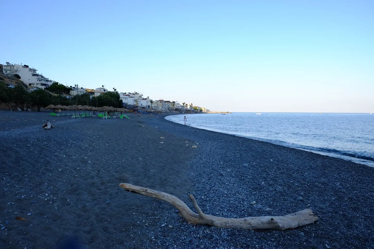 The long grey-sand beach at Myrtos with flat sea and the village along the shore