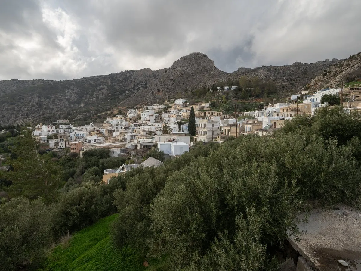 The white houses of Pefki spread on the hillside under bare rock