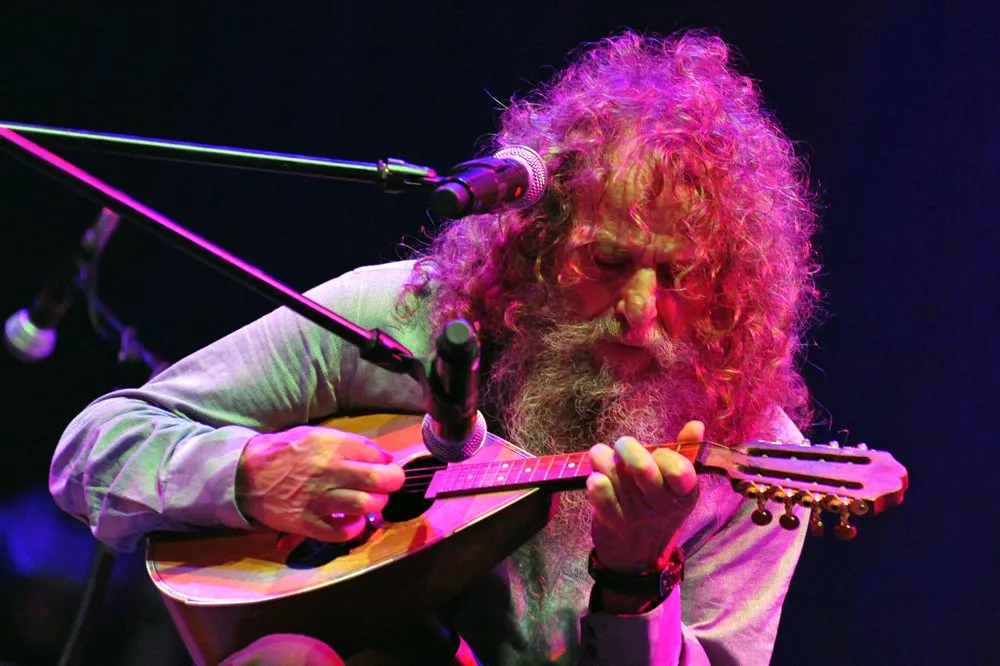 Psarantonis playing the Cretan lyra on stage under coloured lights
