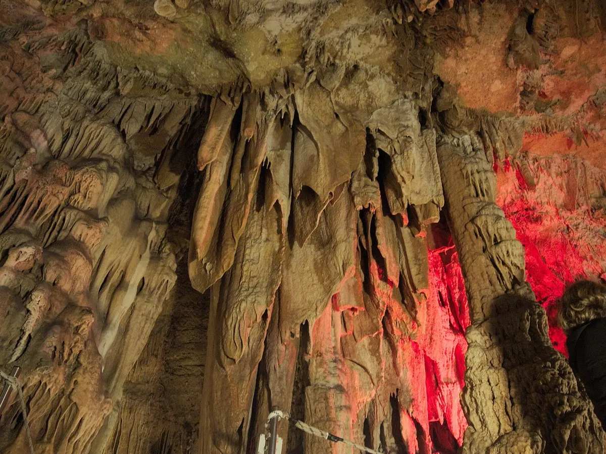 Stalactite and stalagmite columns lit in warm tones inside Sfendoni cave