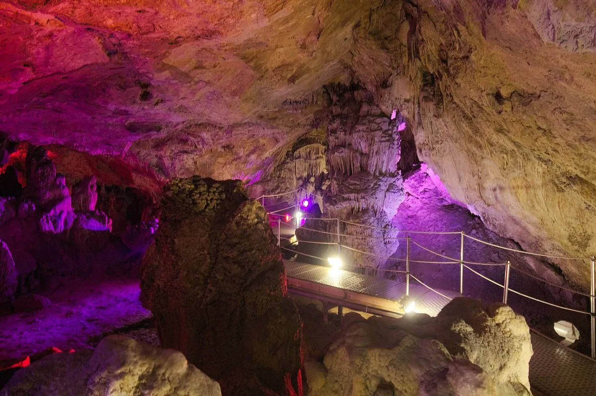 Steel walkways with rope handrails running through a lit cave chamber