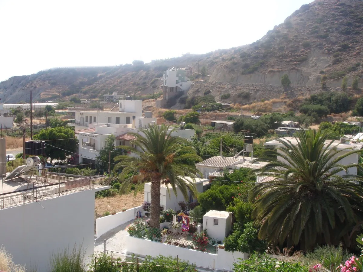 Häuser und Palmen der Feriensiedlung Sidonia, dahinter kahle Hügel