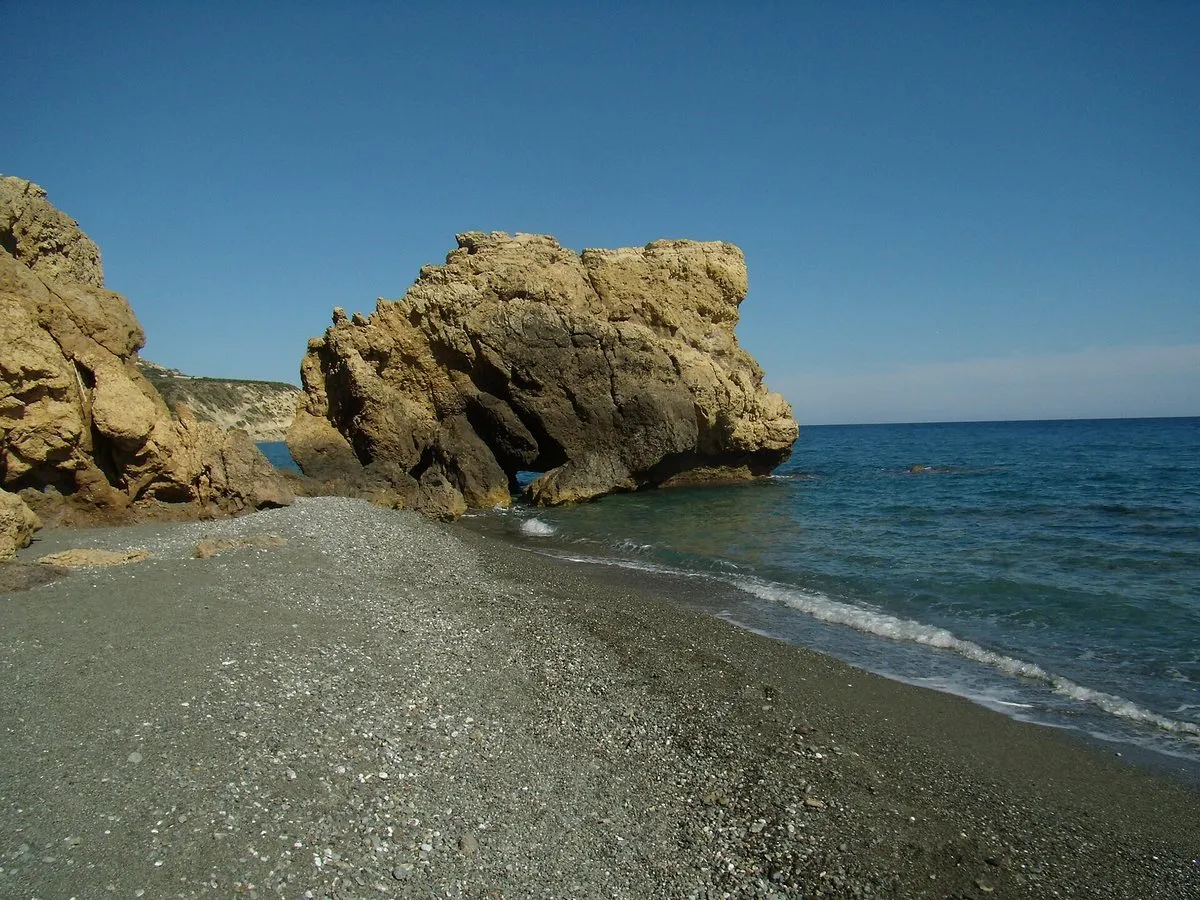 Ein großer Felsen im Meer vor dem grauen Sandstrand bei Tertsa