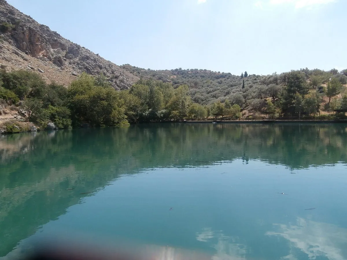Lake Votomos reflecting the olive slopes above Zaros